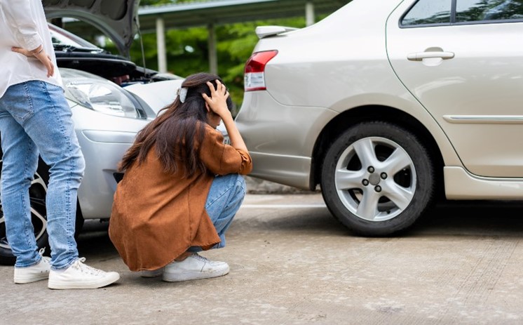 Women checking her car for damages after a car accident