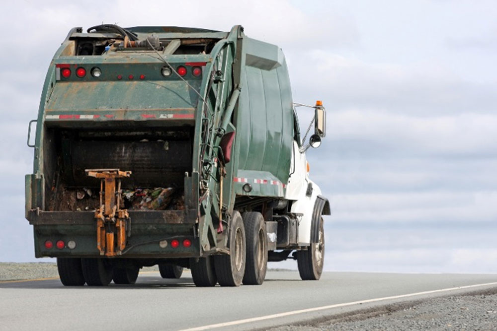 Garbage truck is heading forward on an empty road